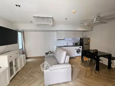 Modern open-plan living room with kitchen, featuring sleek furniture and appliances.