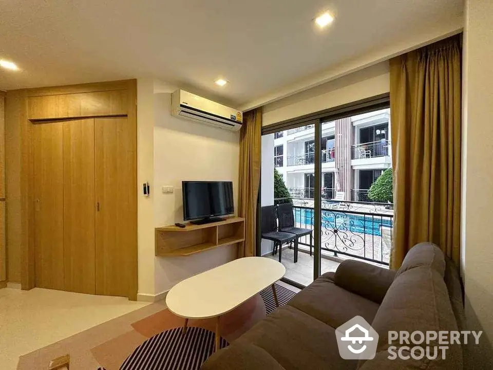 Modern living room with pool view, featuring cozy sofa and flat-screen TV, perfect for relaxation.