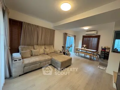 Spacious living room with modern decor and natural light, featuring a cozy sectional sofa and dining area.