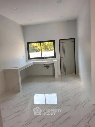 Spacious modern kitchen with sleek marble flooring and large window for natural light.