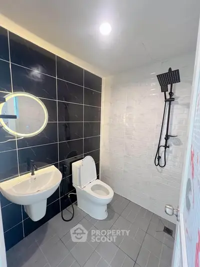 Modern bathroom with sleek black and white tiles, round mirror, and contemporary fixtures.