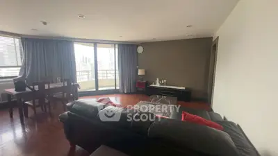 Spacious living room with modern furniture and city view balcony in high-rise apartment.