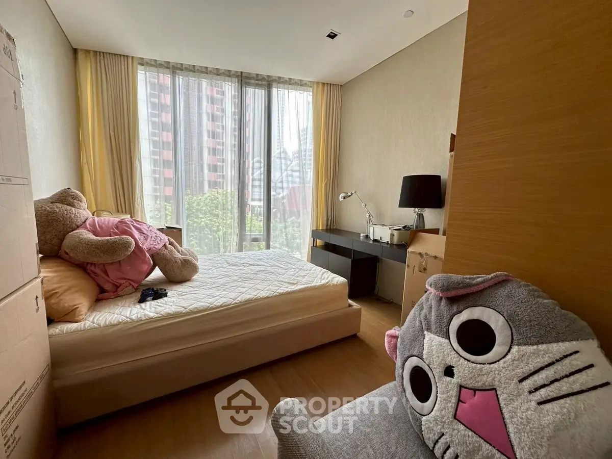 Cozy bedroom with large window and plush toys, ideal for relaxation and comfort.