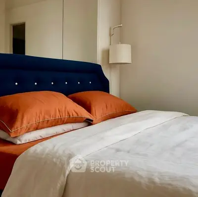 Cozy bedroom with stylish navy headboard and elegant lighting, perfect for relaxation.