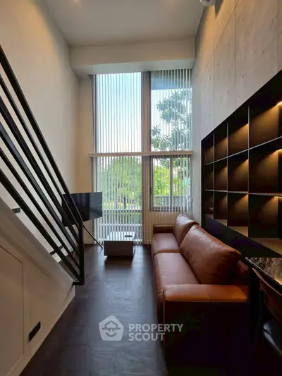 Modern living room with high ceilings, large windows, and stylish furniture in a contemporary apartment.