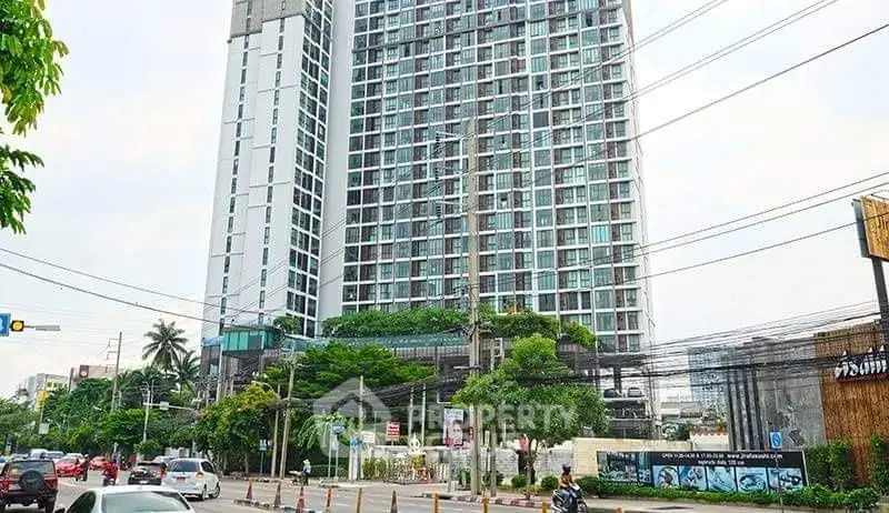 Modern high-rise building with lush greenery and urban street view.