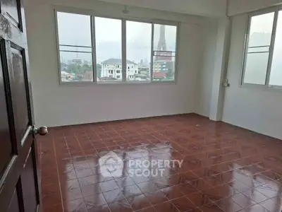 Spacious empty room with large windows offering city views and tiled flooring, perfect for customization.