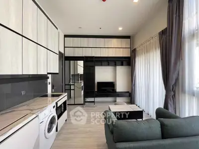 Modern living room with sleek cabinetry and washing machine, featuring large windows and a cozy sofa.