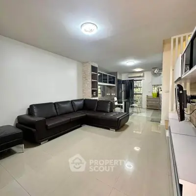 Spacious modern living room with sleek black leather sofa and open layout.