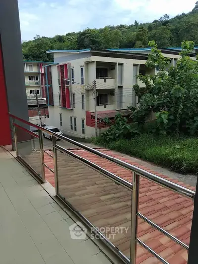 Spacious balcony with scenic view of modern residential buildings and lush greenery.