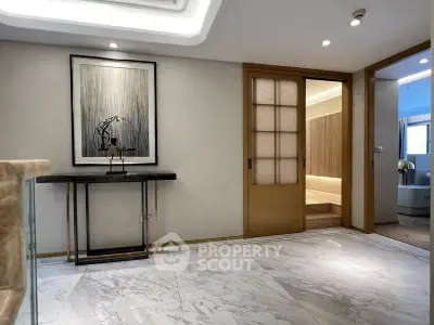 Elegant modern interior with marble flooring and sliding wooden doors, showcasing a sophisticated entryway.