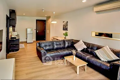 Spacious modern living room with leather sofa and open kitchen layout