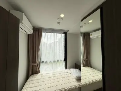 Cozy bedroom with large window and mirrored wardrobe in modern apartment.