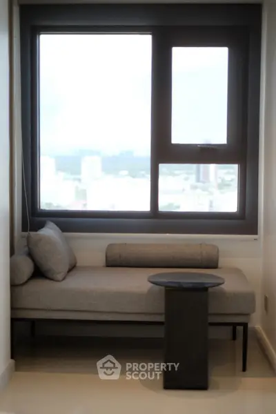 Cozy nook with modern sofa and city view window, perfect for relaxation.