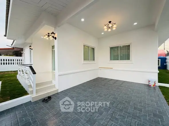 Charming modern home exterior with spacious tiled patio and elegant lighting.