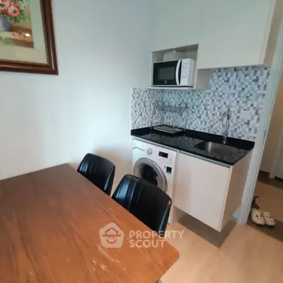 Modern compact kitchen with washing machine and microwave, ideal for urban living.