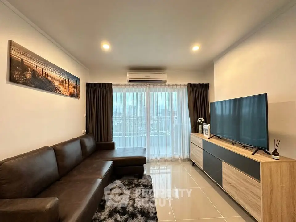 Modern living room with sleek furniture and large TV, featuring a cozy ambiance.
