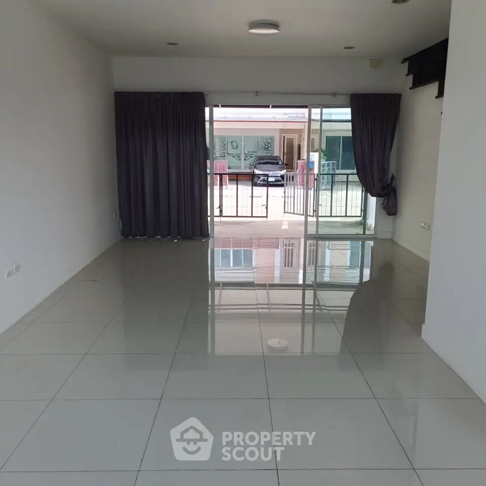 Spacious living room with glossy tiled floors and large sliding glass doors leading to a balcony.