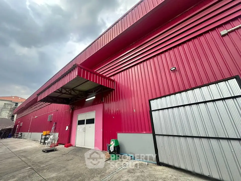 Spacious industrial warehouse with vibrant red exterior and large entry doors.