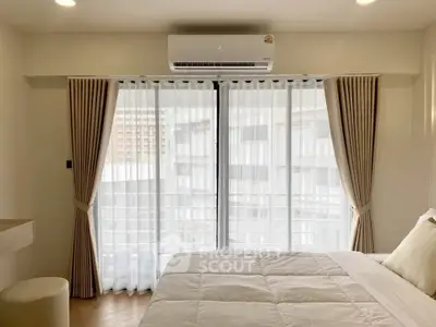 Bright and cozy bedroom with large window and air conditioning, perfect for relaxation.