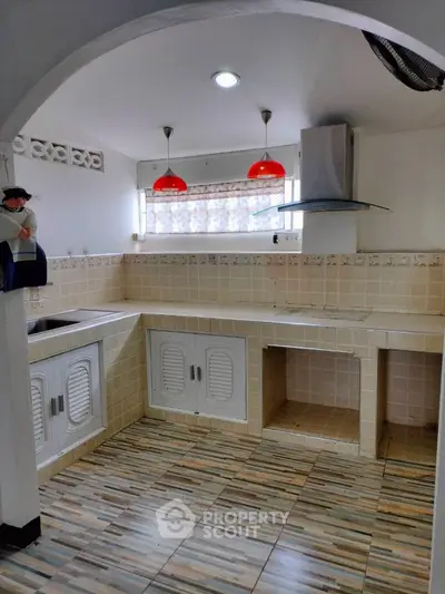 Charming kitchen with tiled countertops and modern range hood in cozy home