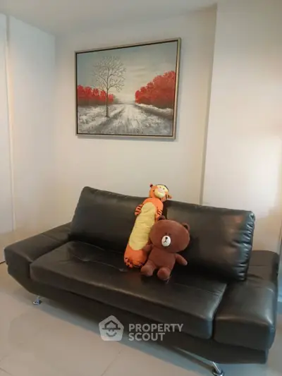 Cozy living room with black leather sofa and charming wall art