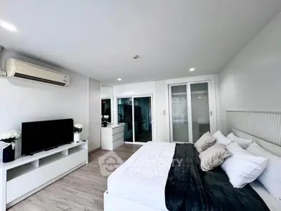 Modern bedroom with sleek design, featuring a comfortable bed, TV, and air conditioning.