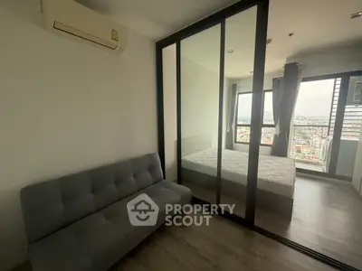 Modern bedroom with glass partition and city view, featuring a cozy sofa and air conditioning.