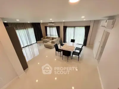 Spacious modern living room with elegant dining area and large windows.