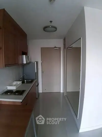Modern compact kitchen with sleek cabinetry and stainless steel appliances in a minimalist apartment.