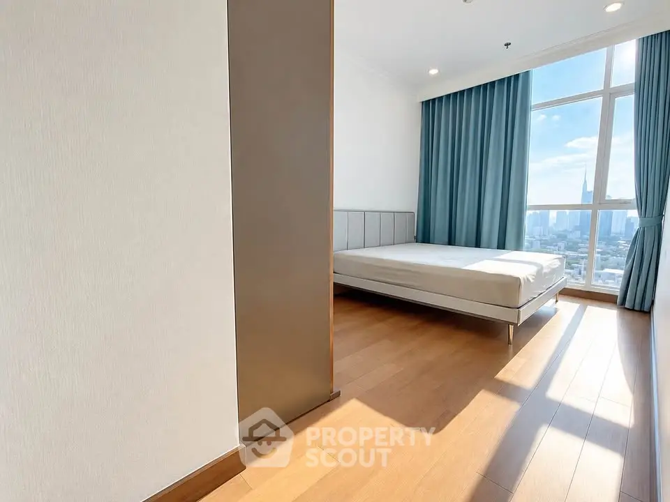 Spacious bedroom with large window offering stunning city views and abundant natural light.