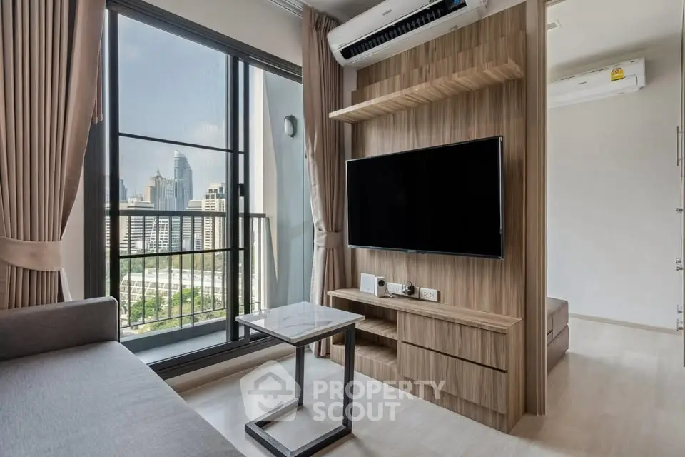 Modern living room with city view, featuring sleek furniture and large window.