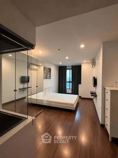 Spacious modern bedroom with wooden flooring and large window view