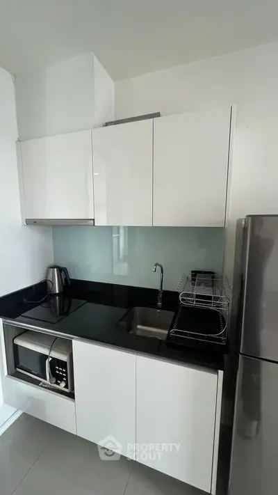 Modern compact kitchen with sleek white cabinets and stainless steel appliances