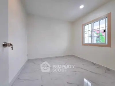 Spacious empty room with marble flooring and large window for natural light.