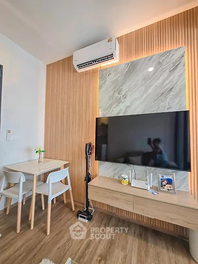 Modern living room with stylish decor, featuring a mounted TV, sleek dining set, and elegant wood paneling.