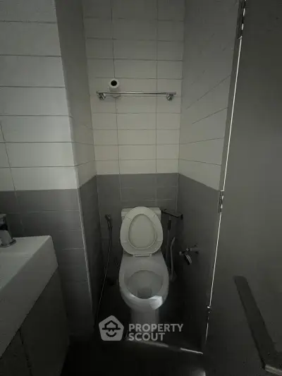 Compact bathroom with modern fixtures and tiled walls, featuring a toilet and a small sink.
