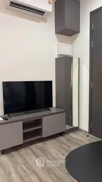 Modern living room with sleek furniture and mounted TV, featuring stylish flooring and air conditioning.