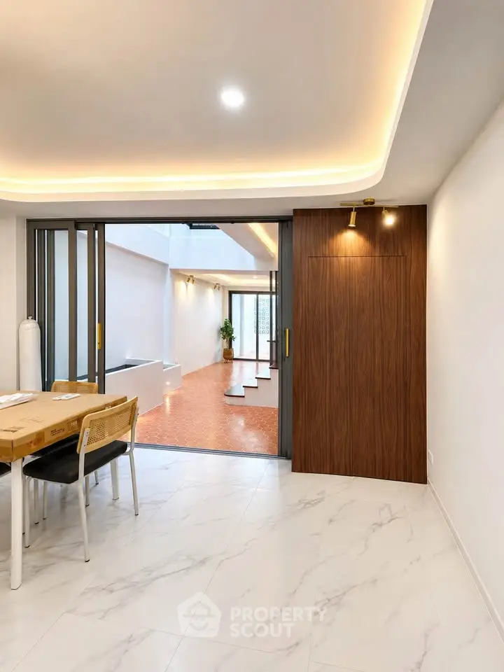 Modern open-plan interior with sliding doors and elegant lighting, showcasing a stylish dining area and spacious hallway.