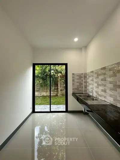 Modern kitchen with sleek design and garden view, featuring a spacious countertop and stylish backsplash.