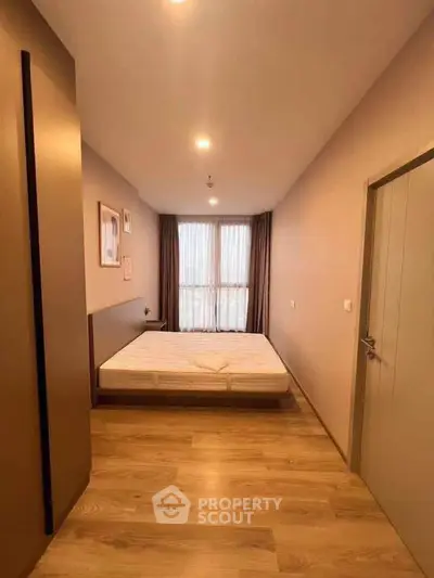 Spacious bedroom with wooden flooring and large window for natural light