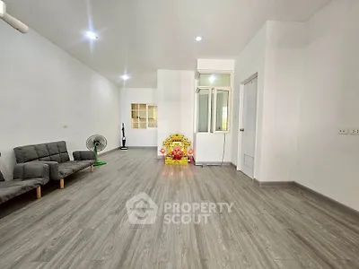 Spacious minimalist living room with modern flooring and simple furnishings.