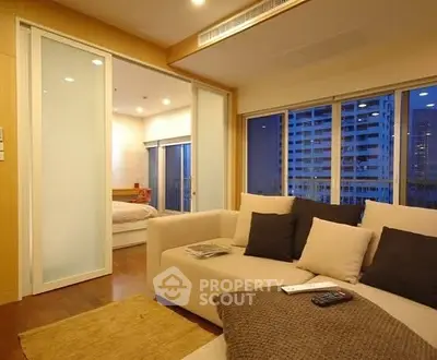 Modern living room with sliding doors and city view, featuring cozy beige sofa and stylish decor.