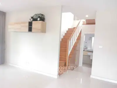 Modern interior with wooden staircase and sleek wall-mounted storage in bright living space.
