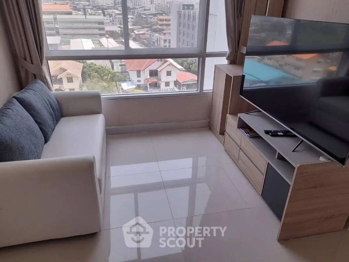 Modern living room with city view, featuring sleek furniture and large windows.