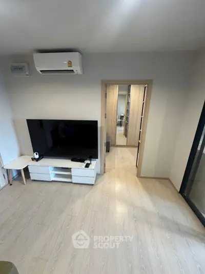 Modern living room with sleek TV setup and air conditioning, showcasing minimalist design.