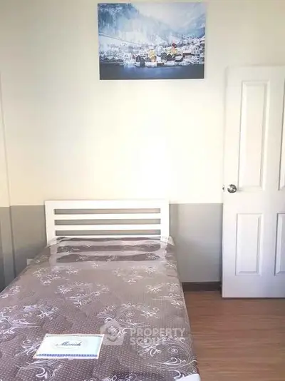 Cozy bedroom with single bed and scenic wall art, perfect for minimalist living.