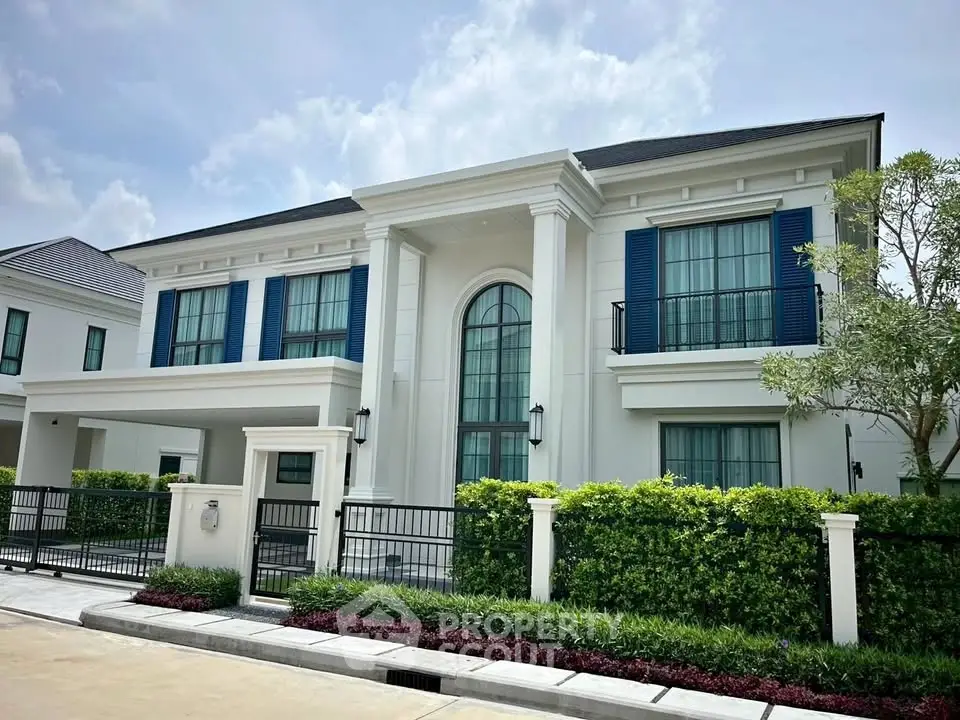 Elegant modern house with blue shutters and lush landscaping