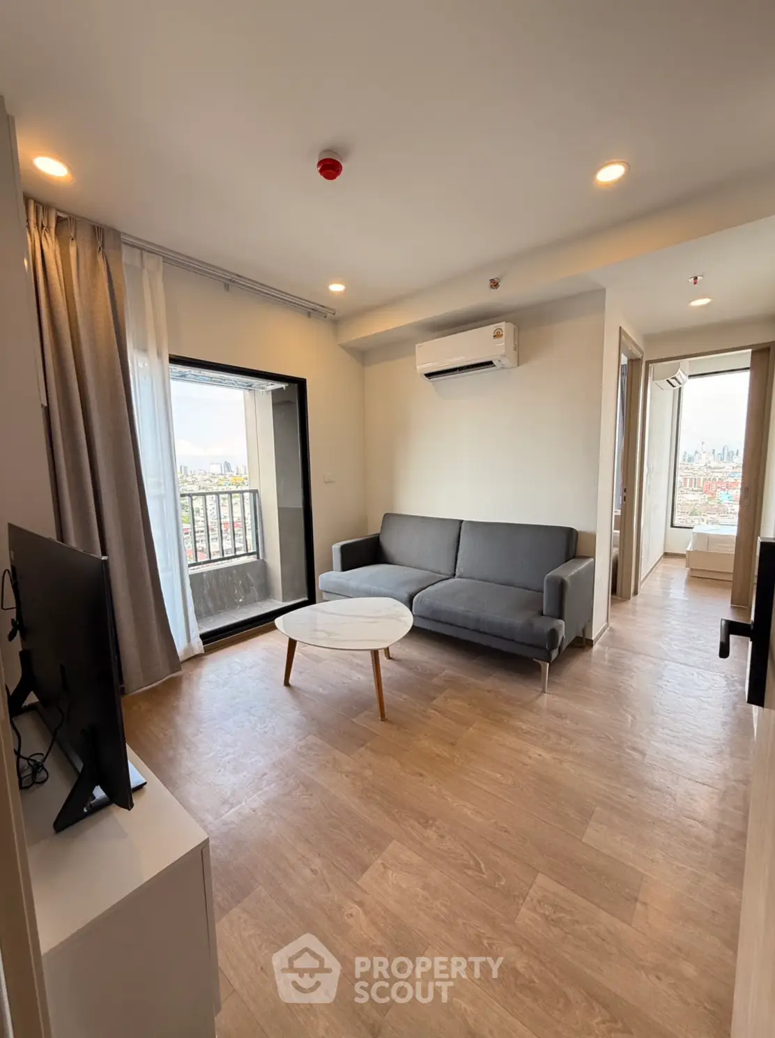 Modern living room with balcony view and sleek furniture in a high-rise apartment.