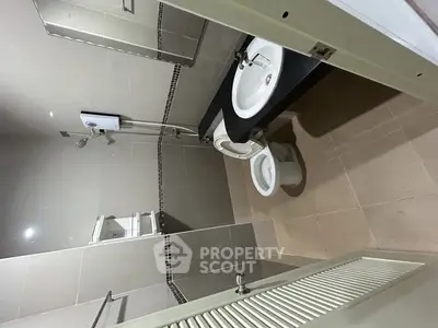 Modern bathroom with sleek fixtures and neutral tiles, featuring a shower and a stylish sink area.